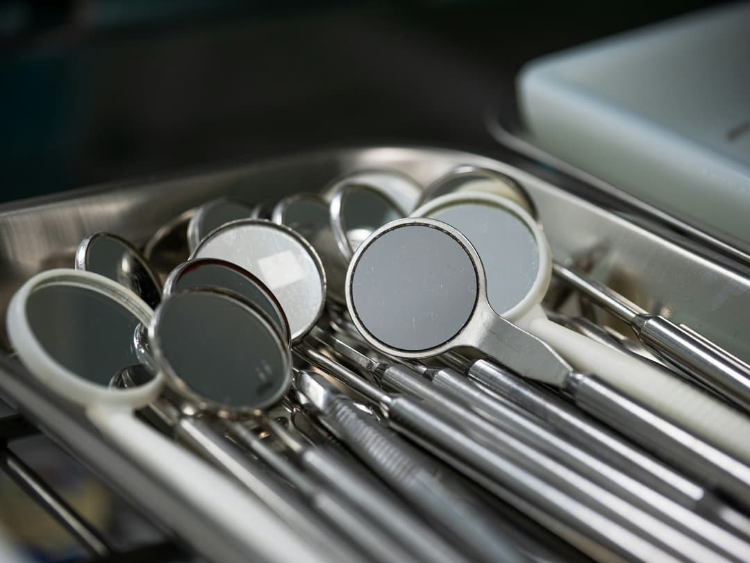 Espelhos clínicos e instrumentos odontológicos organizados em uma bandeja de metal